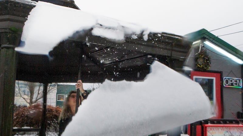 Kacey Miller of Quick Fix Coffee Company in Eugene, Ore., knocks snow and ice from the roof of...