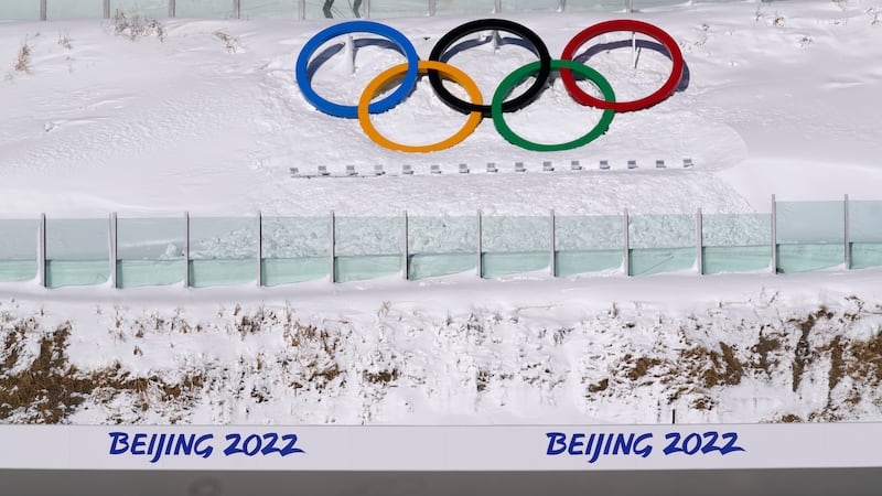 Biathletes skate above the Olympic rings during practice at the 2022 Winter Olympics,...