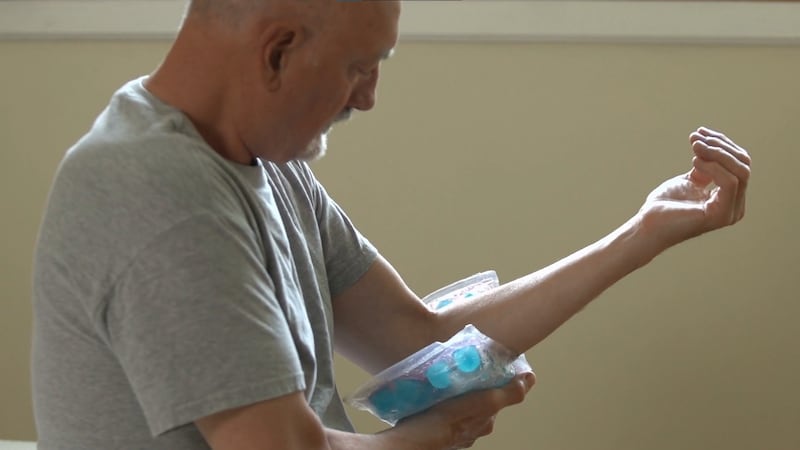 A man applies an ice pack to his elbow to treat pain caused by arthritis.